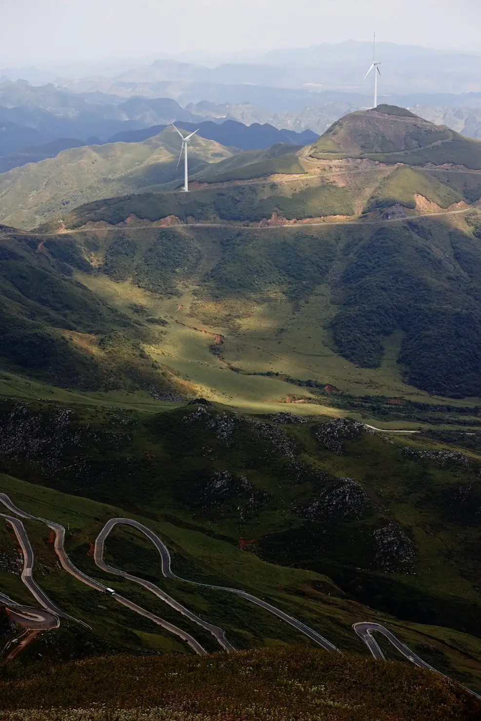 Aerial view of green hills with wind turbines